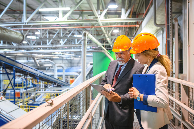 man and woman looking at an inventory list in a warehouse