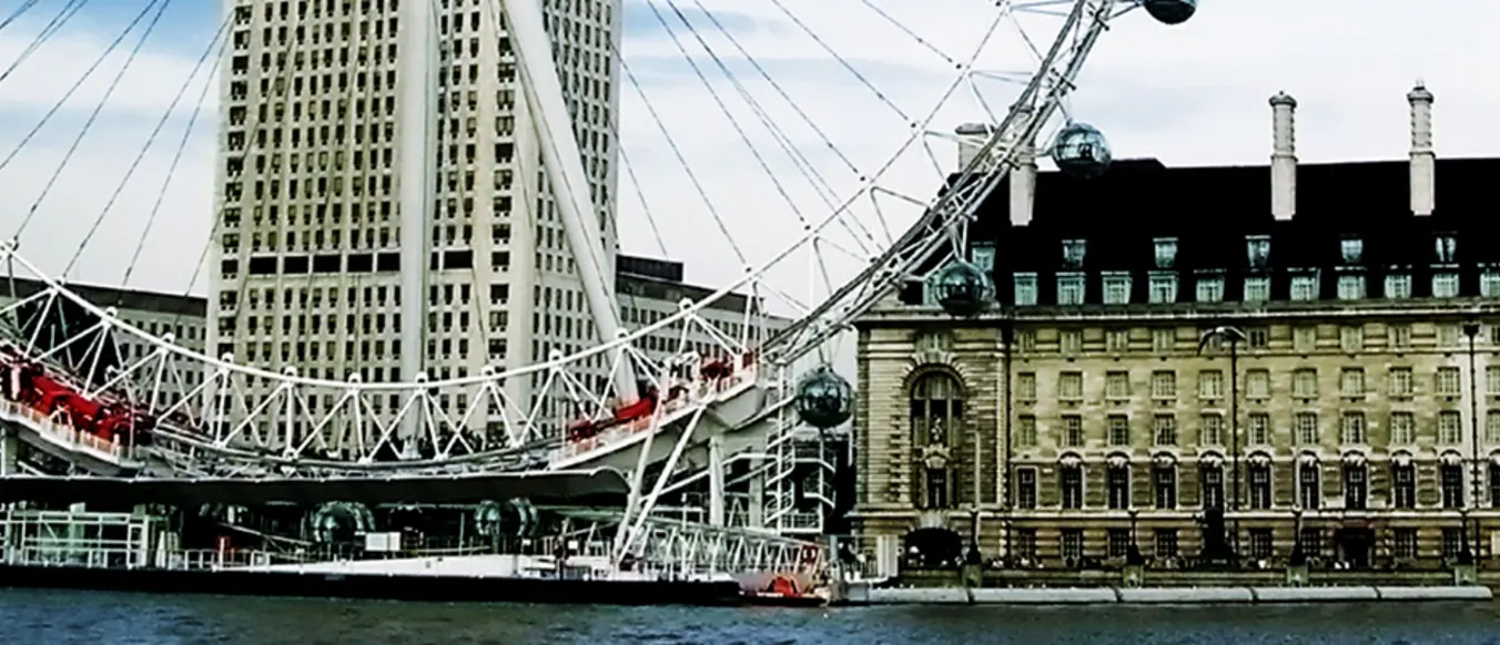 The ferris wheel next to a building on the river