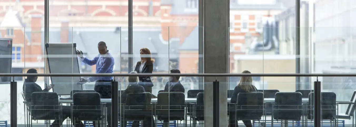 people in conference room as seen through window
