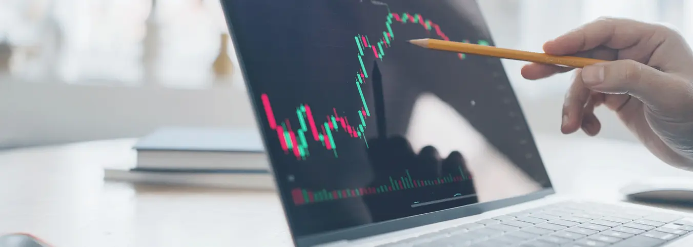 stock chart on computer screen with pointing pencil in hand