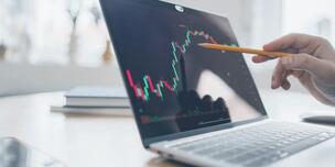 stock chart on computer screen with pointing pencil in hand