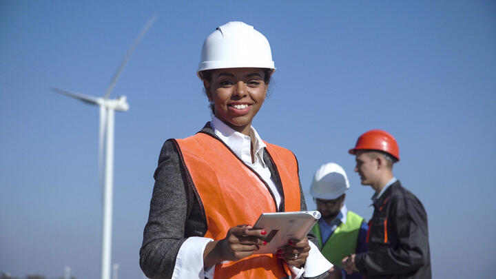 engineer looking at the camera smiling in an open windmill field