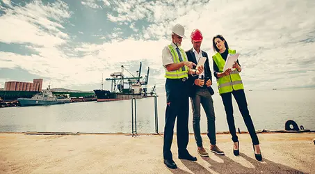 Engineers Standing at port discussing solutions on clipboard
