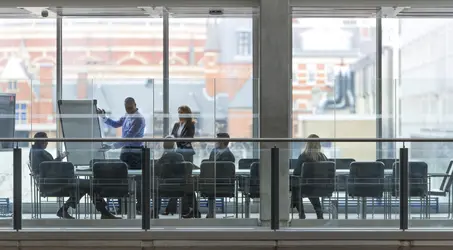 Business room across hallway breezway having conference looking at chart