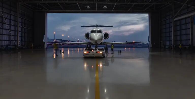 Private jet at entrance to darkened hangar