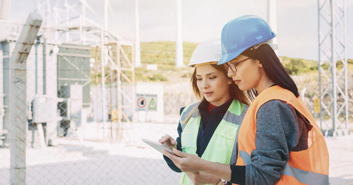 two engineers talking in a wind mill plan