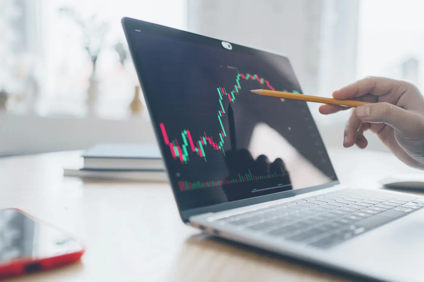 stock chart on computer screen with pointing pencil in hand